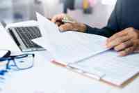 Person mit Dokumenten und Laptop